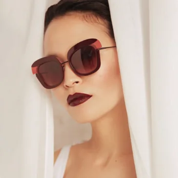 femme portant des lunettes de soleils grandes Caroline Abram modèle Widana en acétate et métal de couleur bordeau et rose