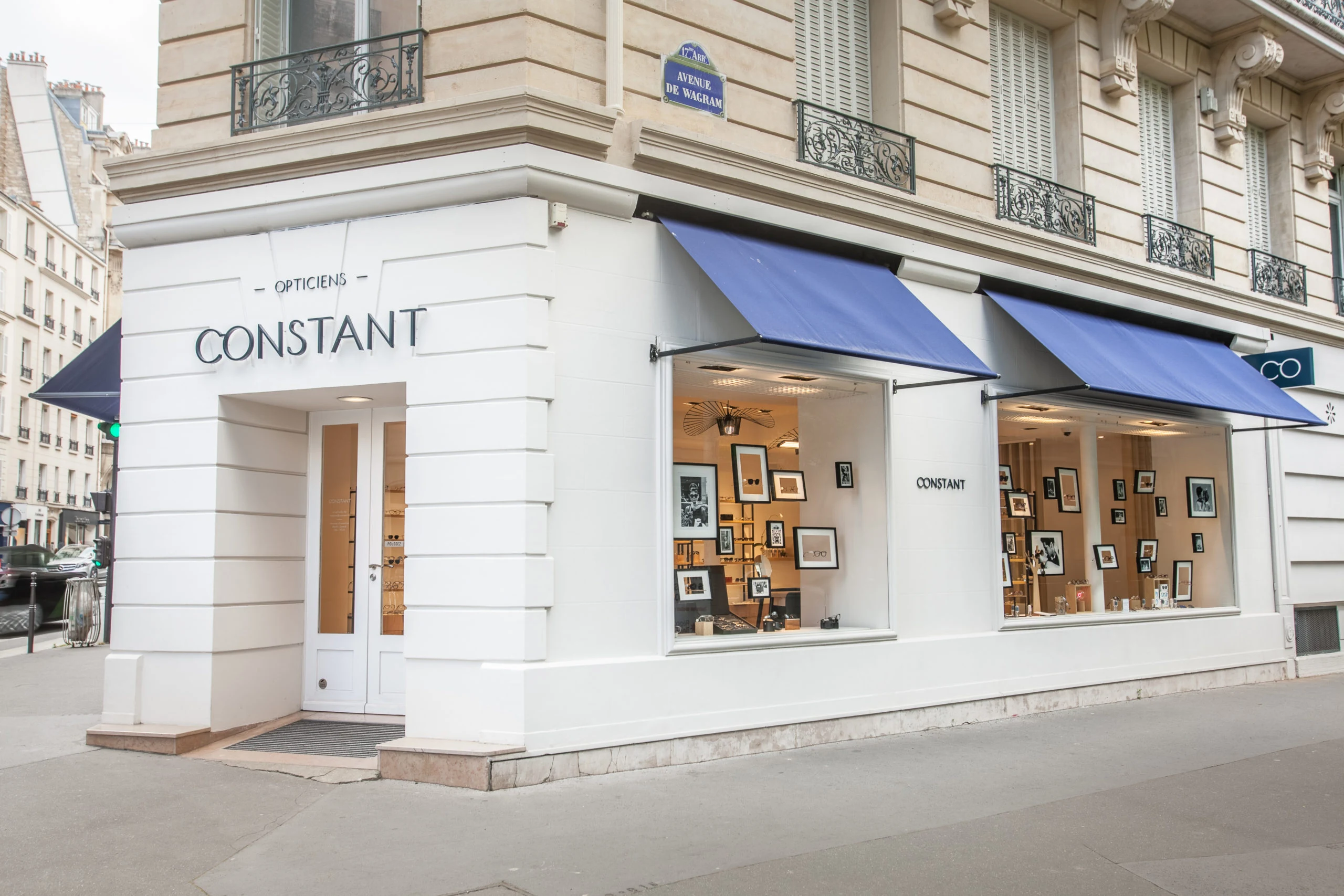 Devanture de CONSTANT Opticiens, angle avenue de Wagram, Paris 17e, stores marine et façade blanche